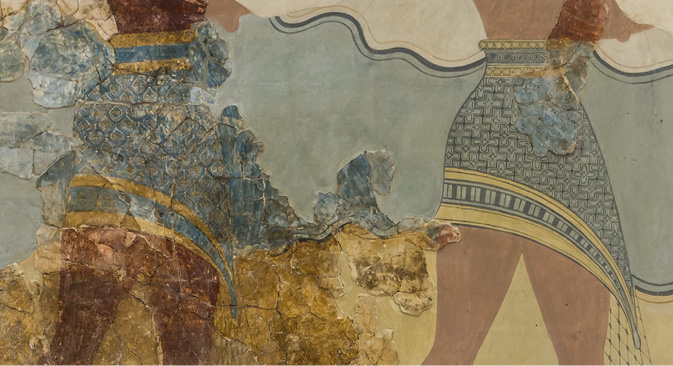 Ancient fresco showing a detail with two figures in patterned skirts. The background is blue with wavy lines.