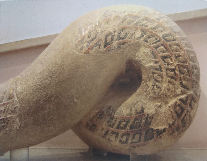 Fragment of a sculpture showing the coil of a huge snake decorated with intricate patterns.