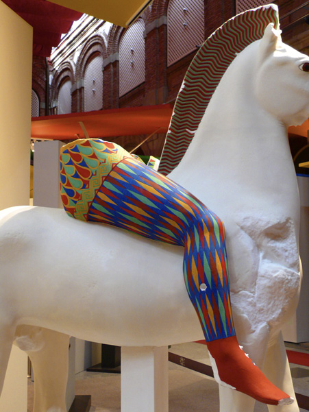 Fragment of the sculpture of a rider on a white horse with reconstructed colourful patterned painting of trousers on his legs.