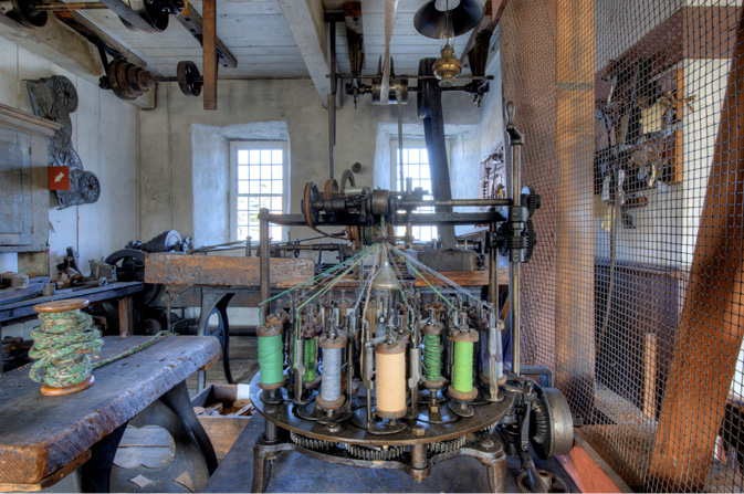 Museum textile workshop with a braiding machine. Spools of colourful threads are arranged intricately.