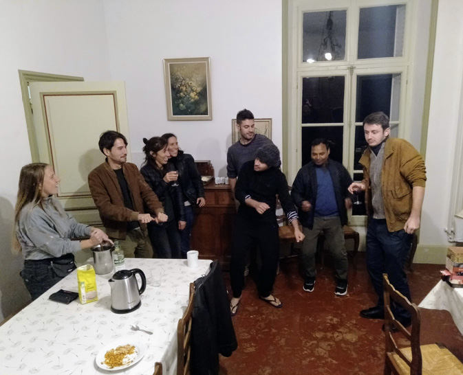 The Technoglob Collective learn dance moves together after dinner in a dining room with a red floor.