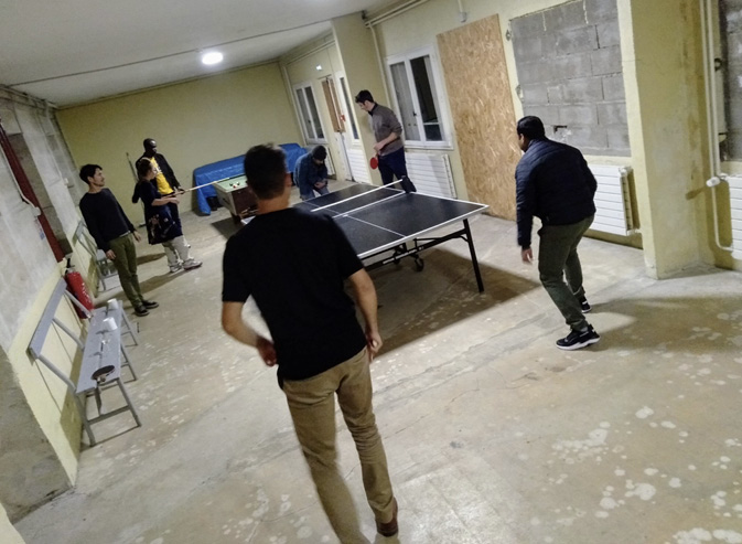 The Technoglob Collective play a game of table tennis in a basement.