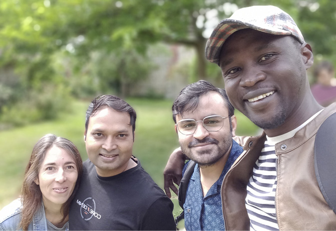 Four of the Technoglob Collective stand with arms around each other in a leafy garden.