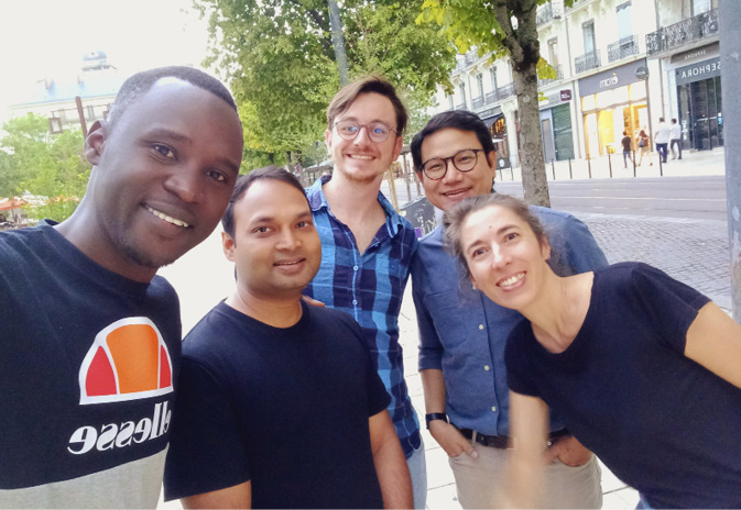 Five of the Technoglob Collective stand together on a tree-lined highstreet.