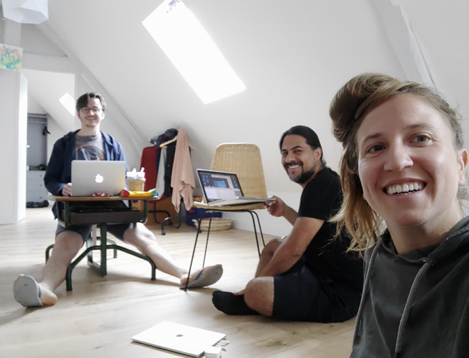 Three of the Technoglob Collective work together on the floor of an attic room filled with light.