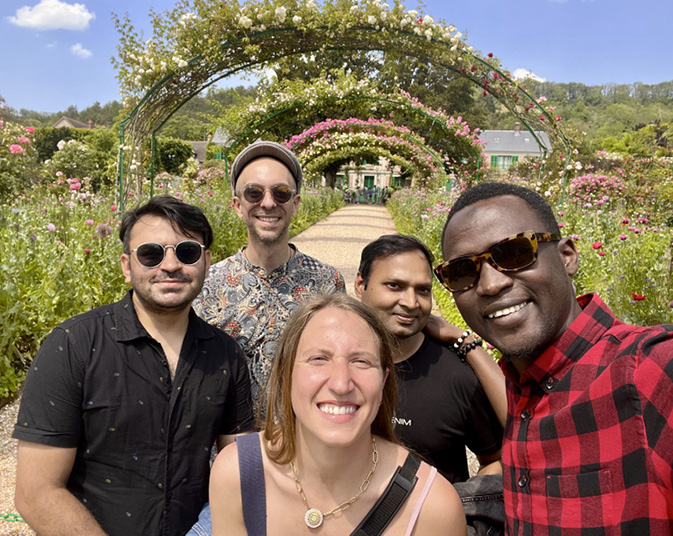 Five of the Technoglob Collective stand together under an archway of flowers.