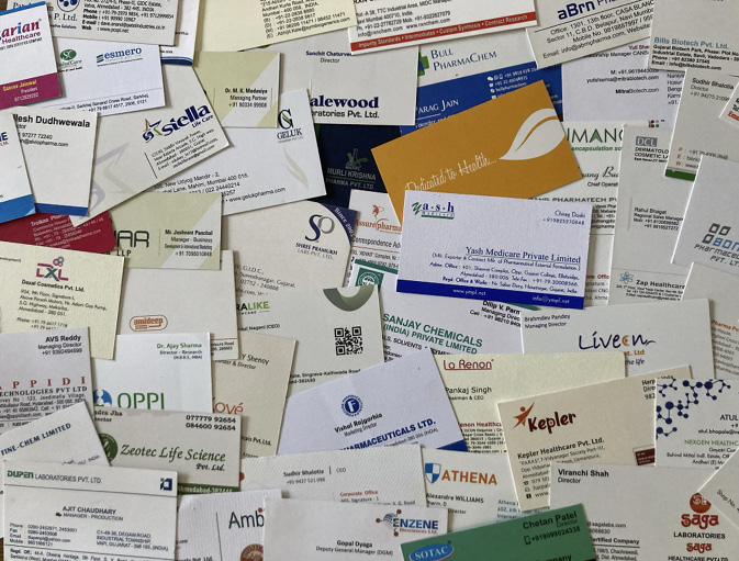 Many visiting cards with different names and logos are spread out across a tabletop.
